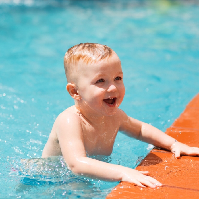 Happy baby enjoying the water during Mini Squad swimming lessons.
