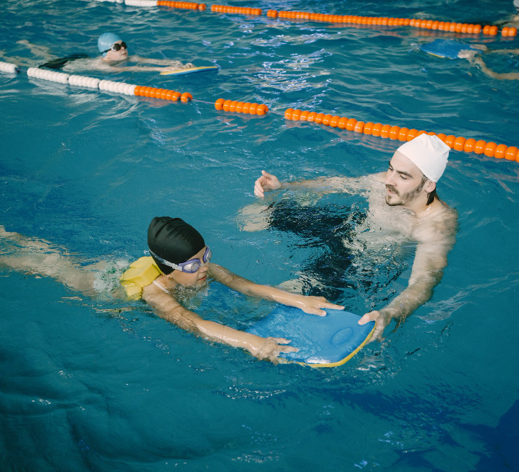 Child learning swimming skills with an instructor in a pool.