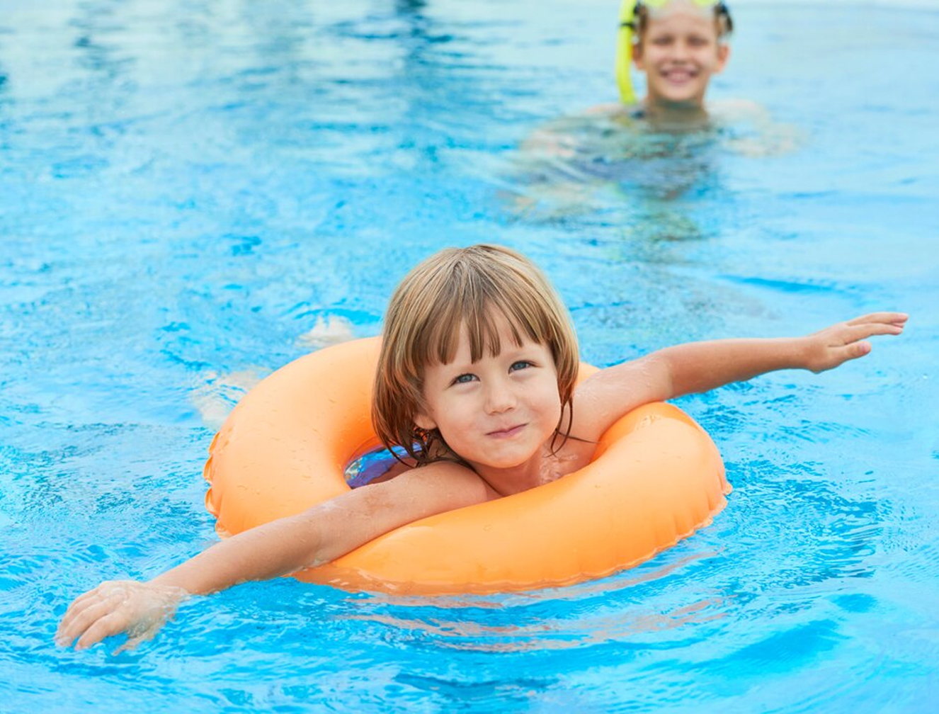 Child practising swimming with a flotation ring.